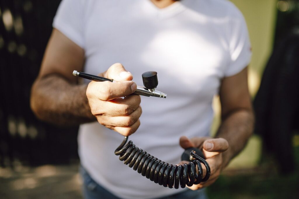 Person hält eine Airbrush mit Spiralschlauch
