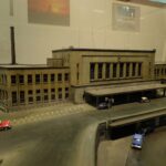 Modell eines großen Bahnhofsgebäudes mit Vorplatz und Autos
