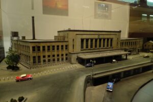 Modell eines großen Bahnhofsgebäudes mit Vorplatz und Autos