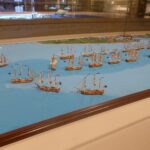 Großes Diorama einer Seeschlacht mit vielen Segelschiffmodellen auf blauem Wasser