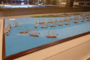 Großes Diorama einer Seeschlacht mit vielen Segelschiffmodellen auf blauem Wasser
