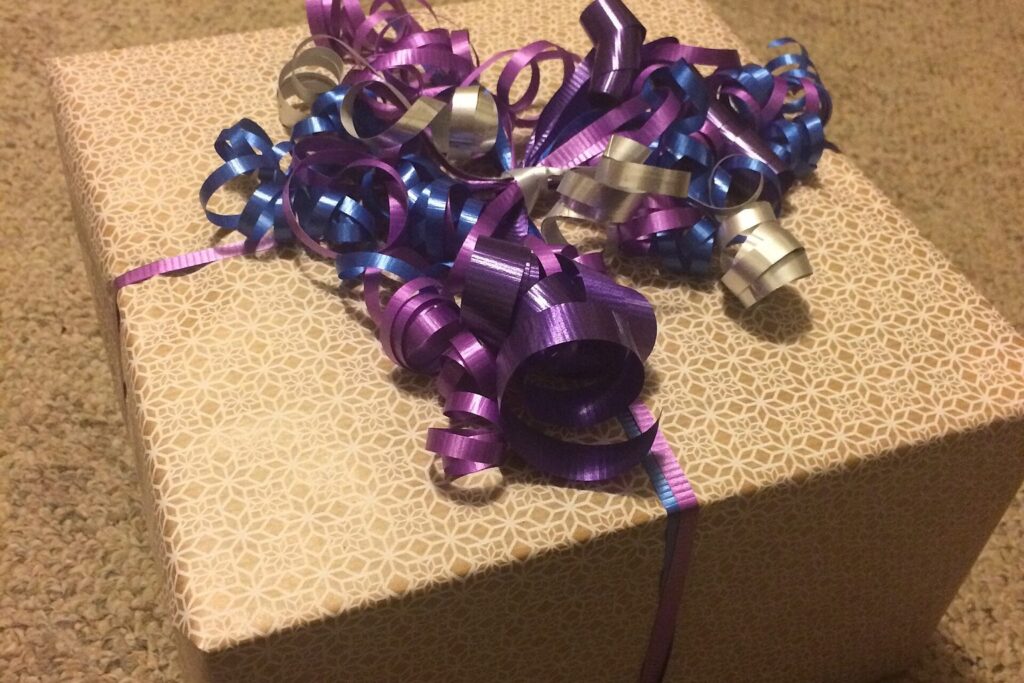 Verpacktes Geschenk mit lila Schleifenband auf einem Tisch