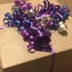 Verpacktes Geschenk mit lila Schleifenband auf einem Tisch