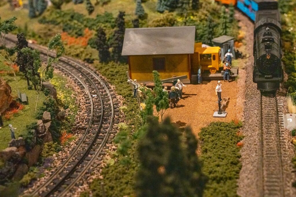 Modellbahnlandschaft mit Gleisen, Bäumen und einem kleinen Bahnhofsgebäude