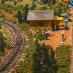 Modellbahnlandschaft mit Gleisen, Bäumen und einem kleinen Bahnhofsgebäude
