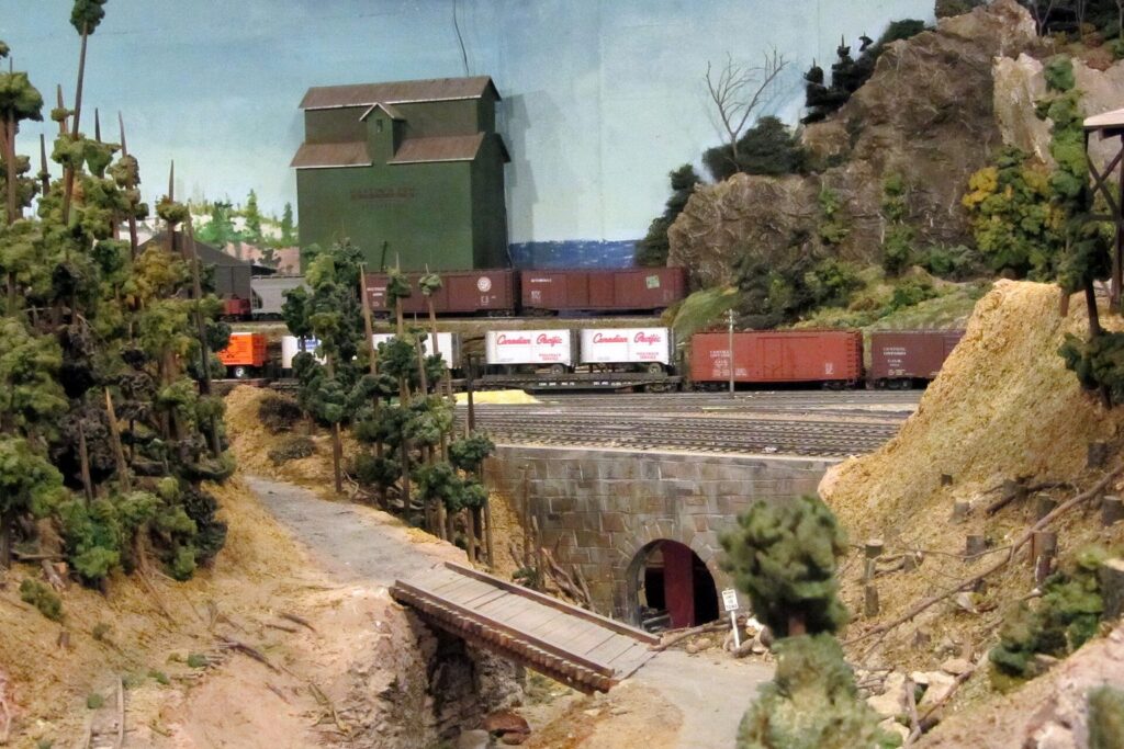 Modelleisenbahn fährt an einer gestalteten Felswand entlang in einen Tunnel