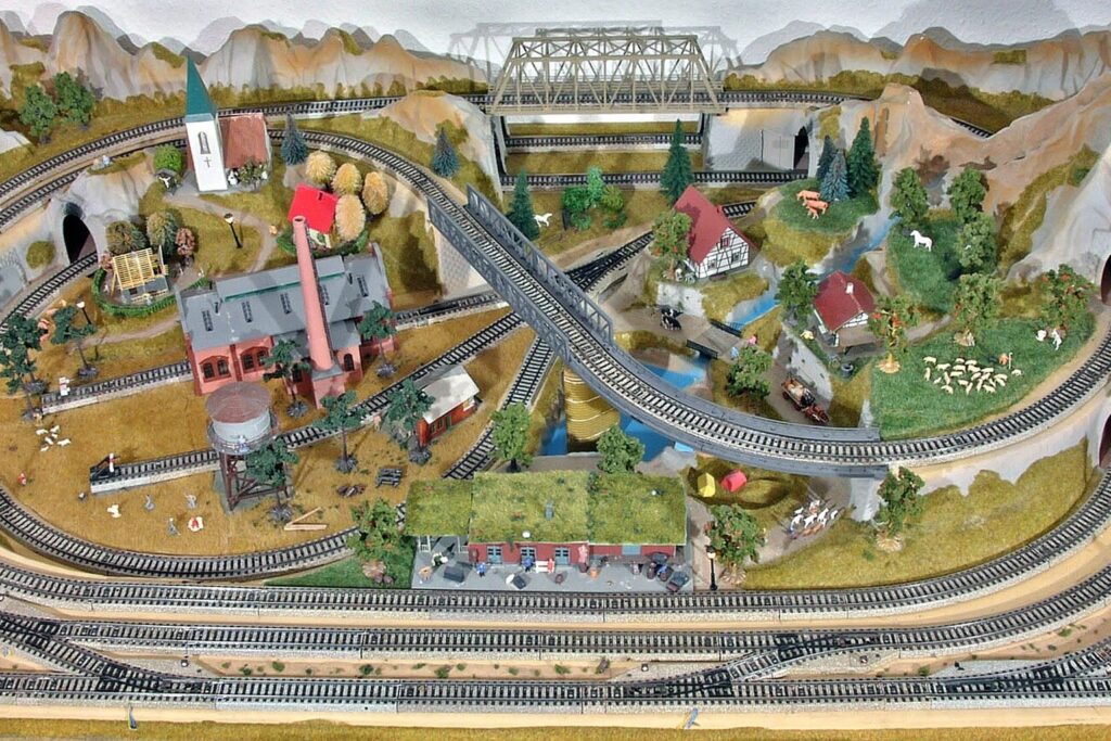 Modelleisenbahn-Anlage mit Bergen, Brücke und Bahnhof von oben