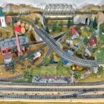 Modelleisenbahn-Anlage mit Bergen, Brücke und Bahnhof von oben