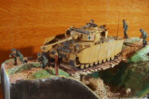 Modell eines historischen Kettenfahrzeugs mit Figuren auf einer Dioramabasis
