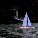 Ferngesteuerte Segelyacht mit roten Segeln auf einem See
