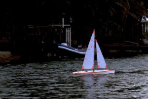 Ferngesteuerte Segelyacht mit roten Segeln auf einem See