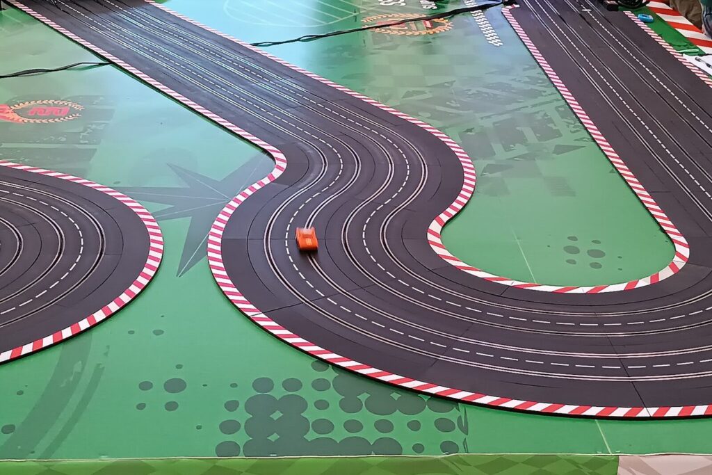 Mehrspurige Slotcar-Rennbahn mit Kurven und einem orangefarbenen Rennauto