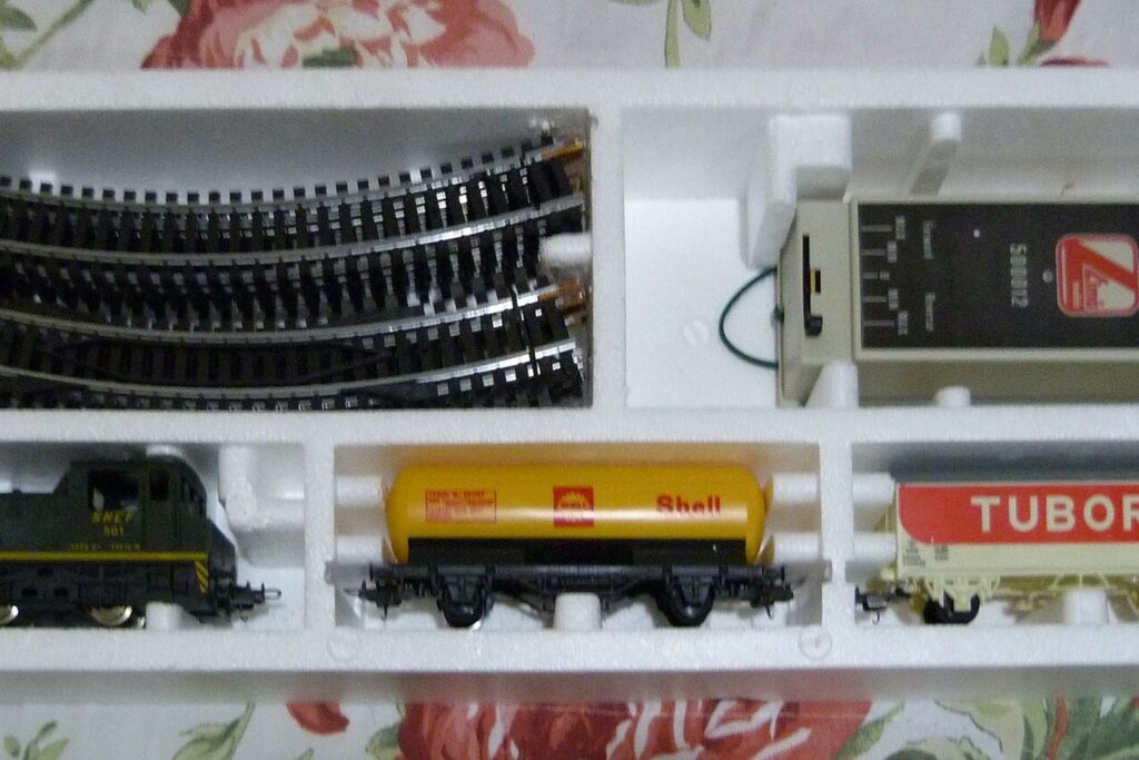Geöffnete Startpackung einer H0-Modelleisenbahn mit Lok, Wagen, Gleisen und Trafo