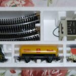 Geöffnete Startpackung einer H0-Modelleisenbahn mit Lok, Wagen, Gleisen und Trafo