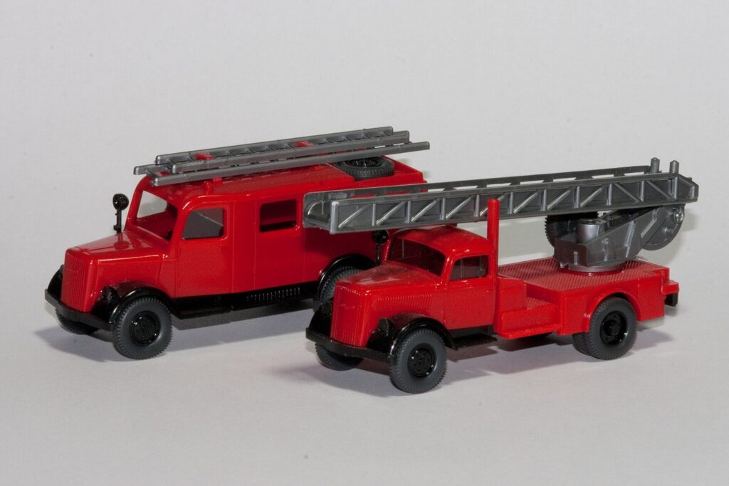 Zwei rote Feuerwehr-Modellautos im Kleinformat nebeneinander