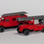 Zwei rote Feuerwehr-Modellautos im Kleinformat nebeneinander