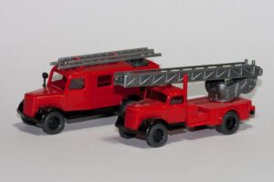 Zwei rote Feuerwehr-Modellautos im Kleinformat nebeneinander